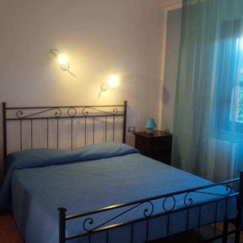 Camera da letto presso Podere Oca Bianca con letto in ferro battuto, vista sul giardino, applique murali e biancheria blu