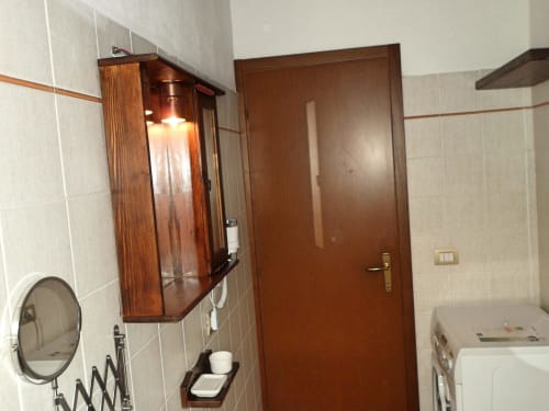 Bagno della camera Camelia a Podere Oca Bianca, con specchiera in legno, lavabo e porta marrone