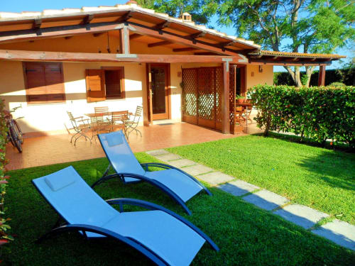 Sala Begonia a Podere Oca Bianca con sdraio blu sul prato, patio in cotto e rustica casa in legno a Pescia Romana