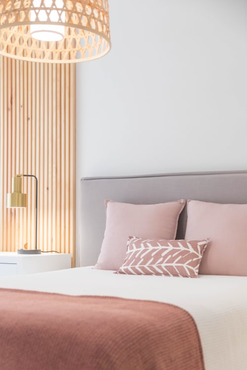 Modern Junior Suite Rose bedroom at French Riviera House Menton with pink pillows, wooden pendant lamp, and gray upholstered