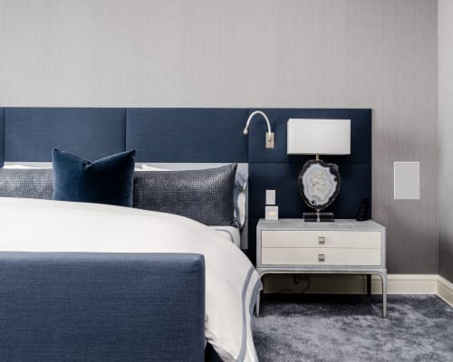 Suite Azul bedroom in Menton with navy upholstered bed, white nightstand, dark accent wall, and modern coastal design