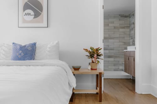 Riviera Suite bedroom at French Riviera House Menton with white bed, blue pillow, wooden nightstand, potted plant, and