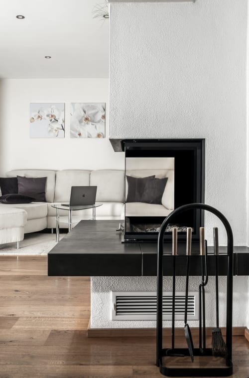 Riviera Suite living room with cream sectional sofa, black fireplace, orchid artwork, and fireplace tools at French Riviera
