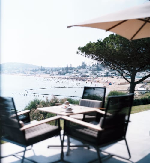 Terrace seating with umbrella overlooking crowded Menton beach and Mediterranean Sea