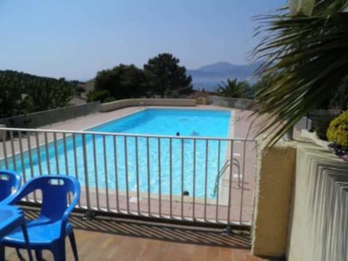 Piscine d'un gîte corse avec chaises bleues, vue sur la mer et palmiers par beau temps