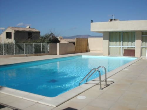 Piscine avec échelle à la location d'appartement à Porticcio en Corse, vue sur la mer en arrière-plan