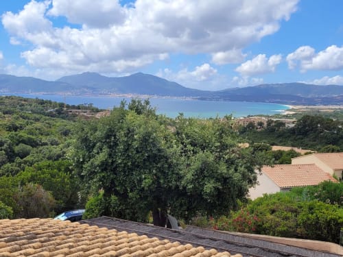 Balcon d'appartement corse avec vue sur la baie de Porticcio, mer turquoise, montagnes et paysage méditerranéen