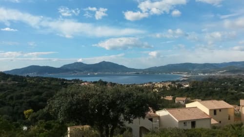 Vue depuis le balcon d'un appartement en Corse surplombant la baie de Porticcio, avec montagnes et mer Méditerranée