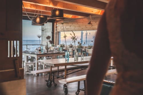 Modern coastal dining area in Menton with sea views, wooden beams, pendant lights, and white furniture