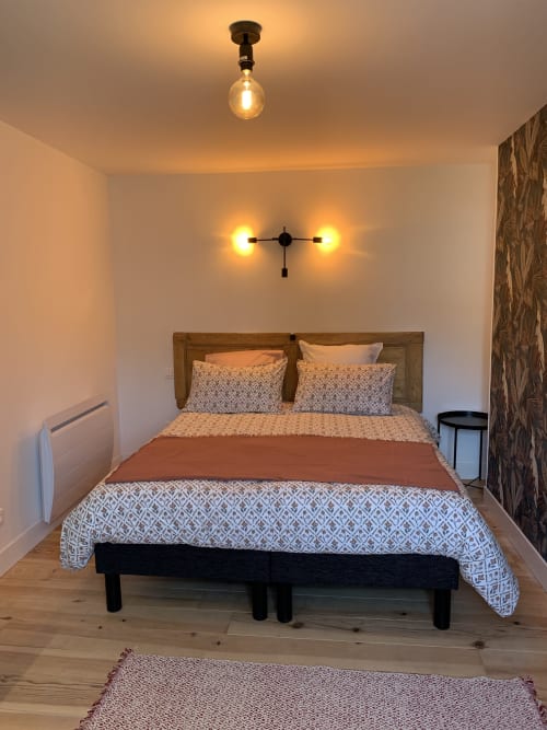 Cozy bedroom at Les Remparts De Joussaume Latour in Château-Thierry with wooden bed, patterned bedding, and warm ceiling
