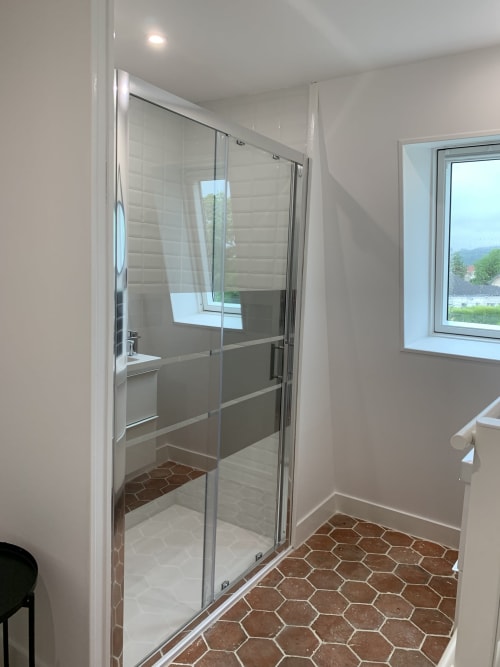 Modern glass shower enclosure with hexagonal tile floor in Le Rat des champs apartment at Les Remparts De Joussaume Latour,