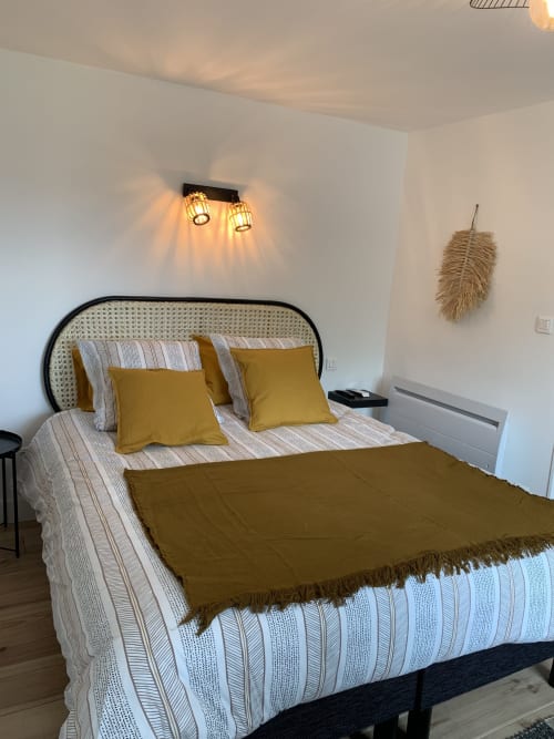 Chambre douillette aux Remparts de Joussaume avec coussins dorés, literie rayée et éclairage ambiant au plafond à Château-Thierry