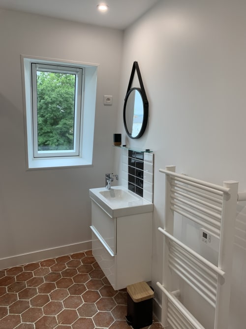 Modern bathroom at Les Remparts De Joussaume Latour with white sink vanity, heated towel rack, and garden window view