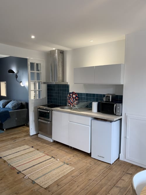 Modern studio kitchen in Suite Le Héron at Les Remparts De Joussaume, Château-Thierry with white cabinets and black tile