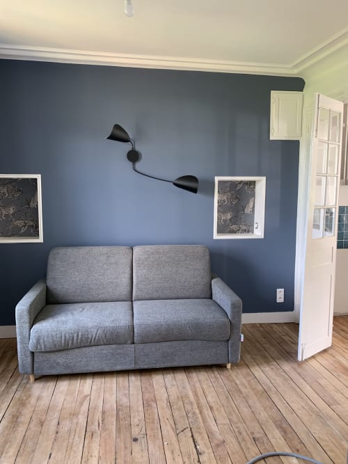 Modern living room in Suite Le Héron at Les Remparts De Joussaume, Château-Thierry with gray sofa and blue accent wall