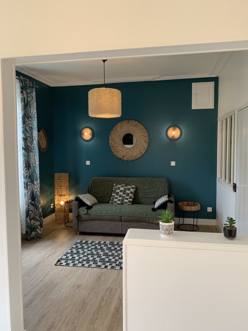 Espace de détente moderne aux Remparts de Joussaume, Château-Thierry : murs bleu canard, canapé gris et touches décoratives tissées