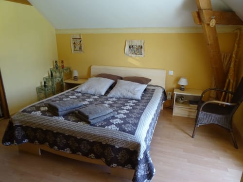 Chambre jaune éclatante avec lit queen-size, literie florale bleue, tables de nuit avec lampes et mobilier en bois chez CafecouetBreizh