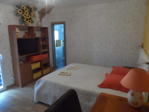 Chambre lumineuse du CafecouetBreizh B&B à Guipry-Messac avec lit, étagères bois, TV et tournesols