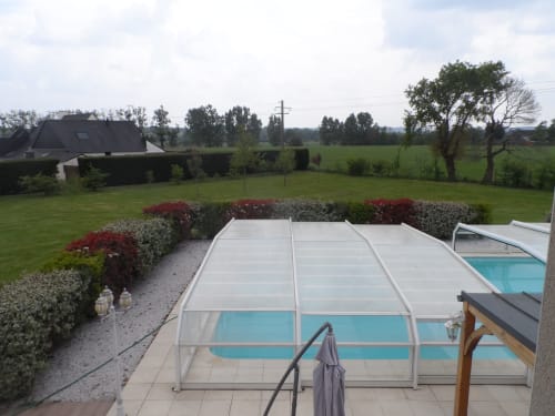 Piscine avec couverture rétractable à la B&B CafecouetBreizh à Guipry-Messac, entourée de jardins paysagés et de vues campestres