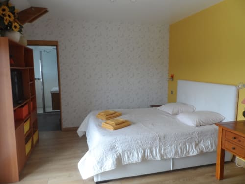 Chambre lumineuse et ensoleillée à CafecouetBreizh B&B à Guipry-Messac avec mur accent jaune, lit blanc et mobilier en bois