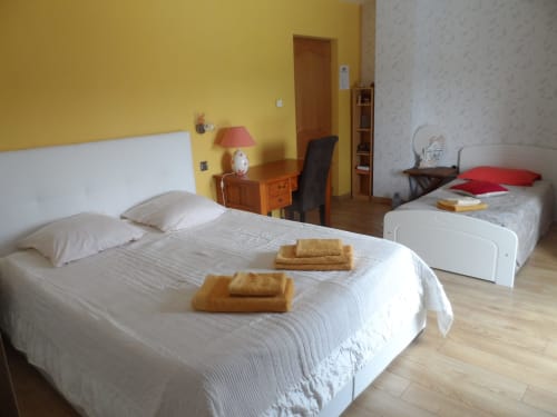 Chambre ensoleillée au gîte CafecouetBreizh à Guipry-Messac avec deux lits, murs jaunes, bureau et parquet