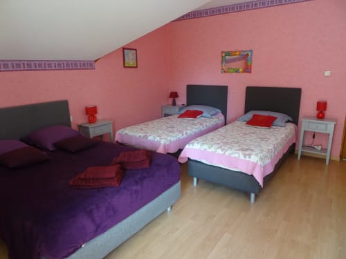 Chambre colorée à la maison d'hôtes CafecouetBreizh à Guipry-Messac avec murs rose, deux lits et canapé violet