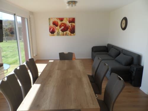 Élégante salle à manger et séjour du Cottage CafecouetBreizh avec table en bois, chaises noires et portes donnant sur le jardin