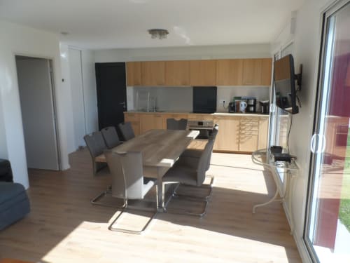 Salle à manger et cuisine contemporaines avec table en bois, chaises noires et lumière naturelle au CafecouetBreizh