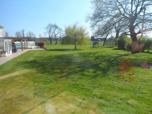 Spacieux jardin du gîte CafecouetBreizh à Guipry-Messac avec aire de jeux, arbres et ciel bleu