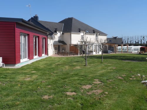 Vue du jardin cottage à CafecouetBreizh, un gîte breton paisible avec pelouse soignée et toit rouge moderne