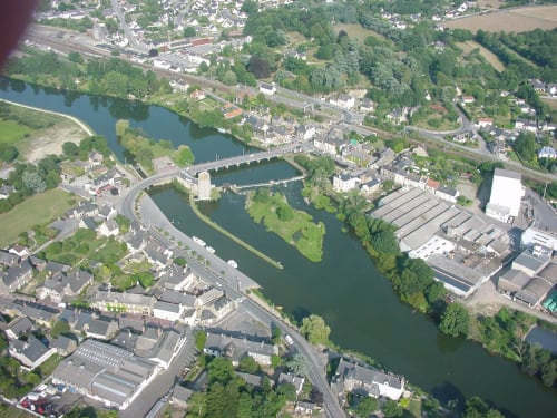 Vue aérienne de la ville riveraine de Guipry-Messac avec pont, paysages verdoyants et bâtiments industriels en Bretagne, France