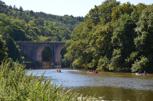 Pont de pierre enjambant une rivière entourée d'arbres verts près de Guipry-Messac, bateaux sur l'eau