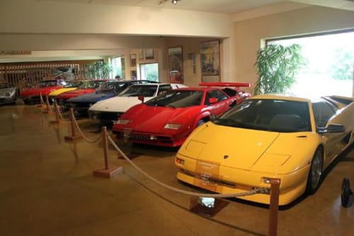 Collection de voitures de sport classiques exposées dans la salle d'exposition de CafecouetBreizh B&B, Guipry-Messac, avec des véhicules jaunes et rouges