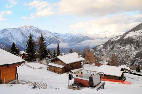 Refuge montagnard enneigé à La Tzoumaz avec chalets en bois, bain à remous et pics alpins