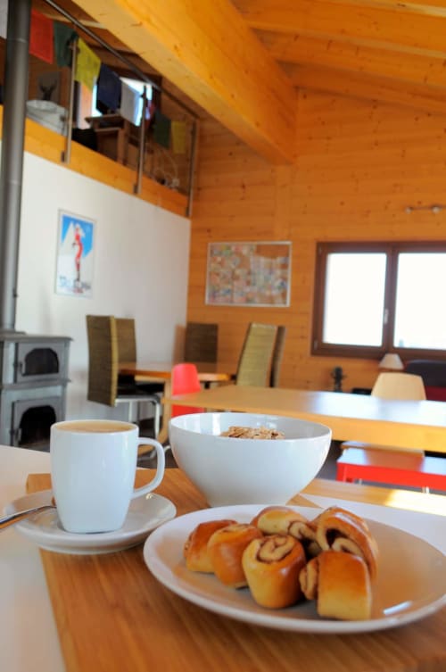 Petit-déjeuner à l'auberge La Tzoumaz : café, viennoiseries et bol de céréales dans une salle à manger chaleureuse en bois