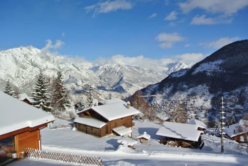 Village alpin enneigé avec chalets en bois et pics montagneux à La Tzoumaz, Suisse