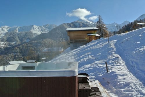 Vue enneigée de La Tzoum'hostel avec pics montagneux et piscine extérieure chauffée à La Tzoumaz