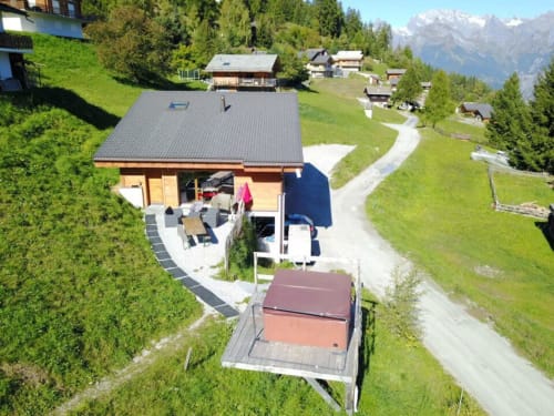 Vue aérienne de La Tzoum'hostel à La Tzoumaz avec paysages montagneux, prairies verdoyantes et chalets alpins