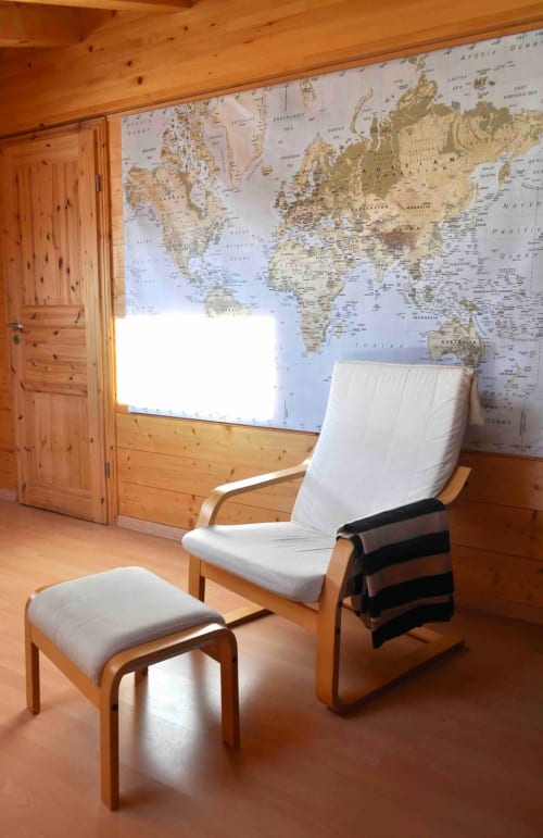 Chambre de chalet en bois à l'auberge La Tzoumaz avec mappemonde murale, fauteuil blanc, ottoman et porte en bois ouverte