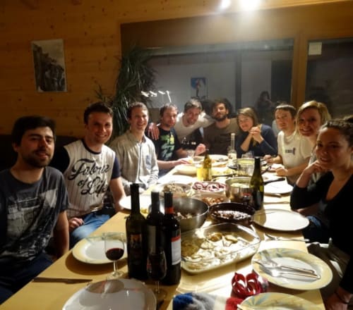 Groupe d'amis partageant un repas convivial à La Tzoum'hostel à La Tzoumaz avec vin et mets