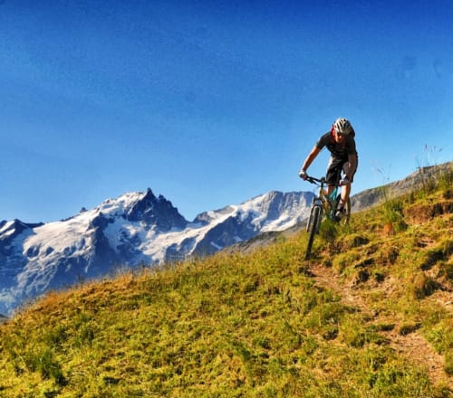 Cycliste en VTT sur un sentier alpin avec pics enneigés près de La Tzoumaz, Suisse