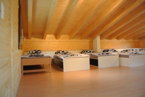 Chambre d'auberge avec vue montagne, plafond en bois, plusieurs lits et parquet à La Tzoumaz.