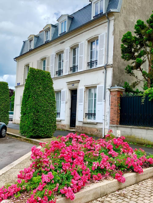 Les Remparts de Joussaume Latour, un gîte à Château-Thierry avec fleurs roses et façade couverte de lierre