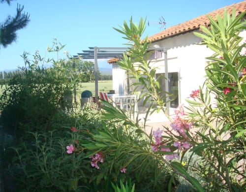 Garden patio with pink flowers and pergola at Gites Mas D'en Ratéro, a bed and breakfast in Thuir, France