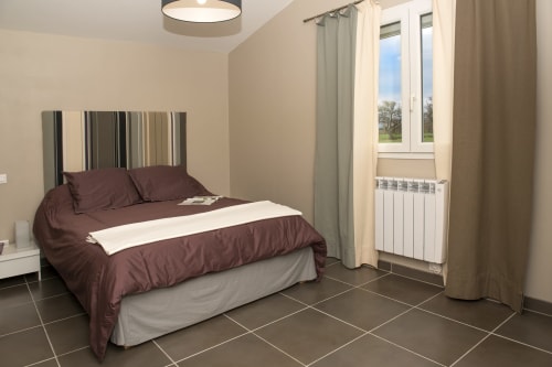 Cottage bedroom at Gites Mas D'en Ratéro in Thuir with queen bed, mountain views through glass doors, and modern amenities