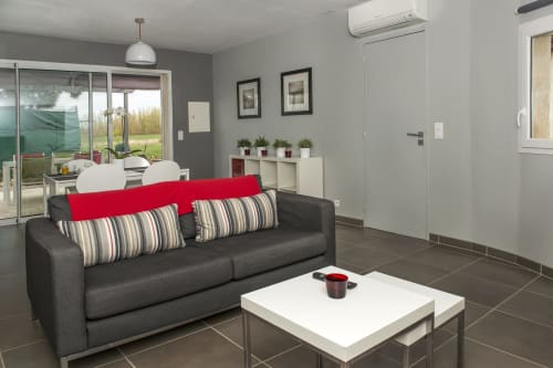Modern living room in Cottage Le Deux at Gites Mas D'en Ratéro, Thuir, with dark sofa, red accents, and garden views