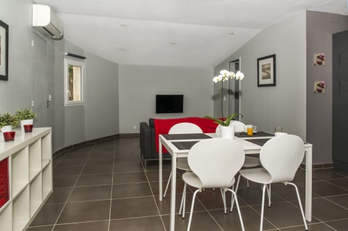 Modern cottage dining area with white chairs, equipped kitchen, living room with red accent, Gites Mas D'en Ratéro, Thuir