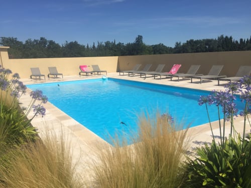Resort swimming pool with blue water, lounge chairs, and mountain views at Gites Mas D'en Ratéro in Thuir, France