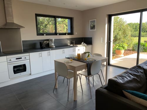 Modern kitchen and dining area in Cottage L'Olivier at Gites Mas D'en Ratéro, Thuir, with white cabinets, black countertops,