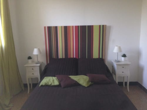 Modern bedroom in Cottage L'Olivier at Gites Mas D'en Ratéro, Thuir, featuring colorful striped headboard and black bedding